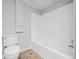 Bathroom featuring white tub and toilet on a stone tile floor, with built-in storage at 28 Fawn Ct, Sharpsburg, GA 30277