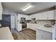 Well-lit kitchen featuring white cabinets, modern appliances, and wood-look flooring at 764 Whitby Dr, Douglasville, GA 30134