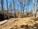 Backyard bordered by woods, featuring remnants of stone landscaping and a wood path at 4665 Guilford Forest Sw Dr, Atlanta, GA 30331