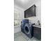 Modern laundry room featuring blue washer and dryer units, stylish cabinetry, and patterned tile flooring at 47 Cuthbert Ln Ne, Acworth, GA 30101