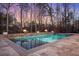 Evening view of the pool, framed by a stone surround, fire bowls and illuminated by soft lighting at 47 Cuthbert Ln Ne, Acworth, GA 30101