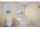 Bathroom featuring a commode, soaking tub, and window for natural light at 3423 Conley Downs Dr, Powder Springs, GA 30127