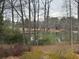 This backyard view overlooks a private lake with mature trees, a chain link fence and native grasses at 3423 Conley Downs Drive, Powder Springs, GA 30127