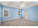 Bedroom featuring neutral blue walls, plush carpeting, and natural light from two windows at 3423 Conley Downs Drive, Powder Springs, GA 30127