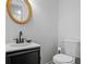 Stylish half bathroom features a round mirror and modern black fixtures, creating a sleek and inviting space at 3798 Valley Brook Rd, Snellville, GA 30039