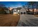Beautiful home exterior with a long driveway, a spacious lawn, and mature trees against a sunset sky at 10780 S Kimball Bridge Xing, Alpharetta, GA 30022