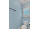 Simple powder room with light blue walls, white toilet, and window with natural light at 10780 S Kimball Bridge Xing, Alpharetta, GA 30022