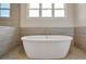 Close-up of a sleek white bathtub with chrome fixtures, complemented by neutral tiled walls at 112 Dallas Mark Drive, Canton, GA 30115