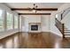 Inviting living room featuring a fireplace with stone surround, built-in shelving, wood beams, and a staircase at 112 Dallas Mark Drive, Canton, GA 30115
