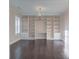 Stylish living room featuring a wall of built-in shelving and dark hardwood floors at 6650 Canyon Cv, Cumming, GA 30028