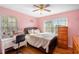 A bedroom with light pink walls, hardwood floors, a ceiling fan, and lots of natural light at 4983 Arcado Sw Rd, Lilburn, GA 30047