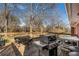 Wooden deck with a stainless steel gas grill, glass table, and chairs, with wooded views at 4983 Arcado Sw Rd, Lilburn, GA 30047