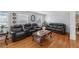 A spacious living room with wood floors and three black leather couches surrounding a marble coffee table at 4983 Arcado Sw Rd, Lilburn, GA 30047