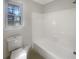 Bright bathroom with a window, toilet, and tiled tub and shower combination at 5926 Brassie Ridge Ln, Ellenwood, GA 30294