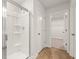 Bright white bathroom with a glass enclosed shower, storage shelving, and wood-look flooring at 2634 Mourning Dove Drive (Lot 41), Grayson, GA 30017