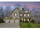 Stunning two-story brick home with a three-car garage and well-manicured lawn at dusk at 3610 Ansley Manor Ct, Cumming, GA 30028