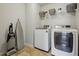 Well-organized laundry room with modern washer, dryer, storage shelves, plus a vacuum and ironing board at 3610 Ansley Manor Ct, Cumming, GA 30028
