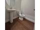 A clean half bath with a pedestal sink, toilet, and sleek wood floors provides modern convenience at 400 Renwood Trl, Johns Creek, GA 30097