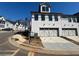 New construction townhome showcasing a two car garage with white brick exterior and paved driveway at 400 Renwood Trl, Johns Creek, GA 30097