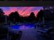 Backyard pool at dusk featuring colorful illuminated sky, with lounge seating, umbrellas, and lush landscaping at 820 Nob Ridge Dr, Marietta, GA 30064