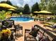 Relaxing poolside area with wicker furniture, vibrant floral decor, and yellow umbrellas for shade at 820 Nob Ridge Dr, Marietta, GA 30064