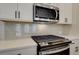 Close-up of a kitchen with stainless steel appliances, tiled backsplash, and quartz countertops at 4521 Twinberry Dr, Powder Springs, GA 30127