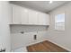 Laundry room featuring white cabinets, neutral walls, a window, and wood look floor at 267 Arwen Drive (Lot 66), Mcdonough, GA 30252