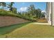 View of the expansive backyard with lush lawn, retaining wall, and privacy fence at 6235 Banyan Trl, Cumming, GA 30028