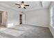 Spacious bedroom features a ceiling fan, tray ceiling, carpeted floor, and natural light from a window and open doorway at 6235 Banyan Trl, Cumming, GA 30028