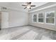 Bright bedroom features multiple windows providing natural light, a ceiling fan, neutral walls, and comfortable carpeting at 6235 Banyan Trl, Cumming, GA 30028