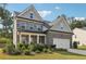 A cozy two-story house with a two-car garage, gray brick facade, and lush landscaping at 6235 Banyan Trl, Cumming, GA 30028