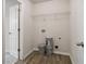 Small utility room has wood-look flooring, shelving, and hookups for a washer and dryer unit at 6235 Banyan Trl, Cumming, GA 30028