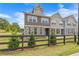 View of a two-story townhome showing stone and gray siding with a black fence and lawn at 6701 Cedar Glen Rd, Peachtree Corners, GA 30071