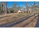 Large backyard with mature trees and distant house with deck, bathed in sunlight at 436 Tarpley Ave, Bowdon, GA 30108