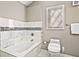 Bright bathroom featuring a tiled soaking tub and white toilet at 1684 Braeburn Se Dr, Atlanta, GA 30316
