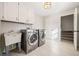 Well-lit laundry room with tile floors, washer, dryer, utility sink, and storage cabinets at 2833 Landing Way, Marietta, GA 30066