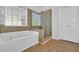 Bathroom with a tub, glass shower, and double doors, blending relaxation with functionality at 6640 Grove Crossing Ct, Cumming, GA 30028
