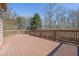 Spacious wooden deck with railing overlooking a lush backyard with mature trees providing privacy at 6640 Grove Crossing Ct, Cumming, GA 30028