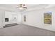 Large carpeted main bedroom with a ceiling fan, tray ceiling, and adjoining living room at 1861 Lacebark Elm Way, Lawrenceville, GA 30045
