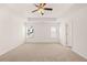Bright and airy bedroom featuring plush carpeting, a tray ceiling with ceiling fan, and ample natural light from two windows at 1838 Lacebark Elm Way, Lawrenceville, GA 30045