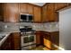 Kitchen showcasing stainless steel appliances, wood cabinets, and tiled backsplash at 2715 Maple Park Pl # 30, Cumming, GA 30041