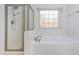 This bathroom shows an enclosed shower and a white soaking tub by a window with a view of the trees outside at 1231 Wildcliff Cir, Atlanta, GA 30329