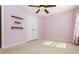 This bedroom has neutral carpet, soft pink walls, two sunny windows, a ceiling fan, and several shelves at 1231 Wildcliff Cir, Atlanta, GA 30329