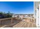 A wooden deck with railing offers outdoor living space and a view of the neighborhood, set against a clear blue sky at 1530 Avalon Creek Rd, Sugar Hill, GA 30518