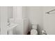 Well-lit powder room with a pedestal sink, toilet, and convenient towel rack at 1530 Avalon Creek Rd, Sugar Hill, GA 30518
