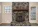 Close up of the stone fireplace, wooden mantel, and window with natural light at 1312 La Mesa Dr, Lawrenceville, GA 30043