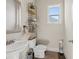 Bathroom with a pedestal sink, toilet, and decorative shelving with various decorations at 4590 Gablestone Xing, Hoschton, GA 30548