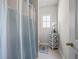 Bathroom with light blue shower curtain and tan tile flooring next to a white storage cabinet at 4590 Gablestone Xing, Hoschton, GA 30548