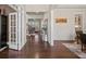 Spacious hallway with hardwood floors, wainscoting, open staircase, and views into the living room and kitchen at 4590 Gablestone Xing, Hoschton, GA 30548