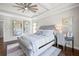 This main bedroom features a tufted headboard, ceiling fan, and a desk with a chair at 4590 Gablestone Xing, Hoschton, GA 30548